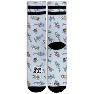 Front view of fun sea themed socks with characters floating on surfboards surrounded by sharks by american socks 