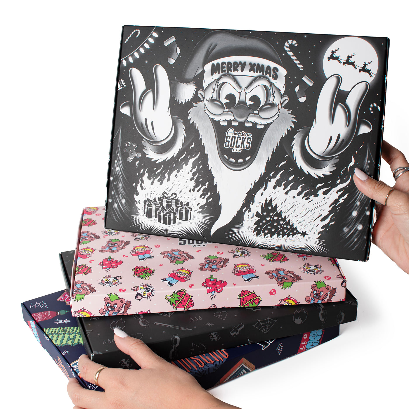 Four cool piled up gift boxes with different designs held by hands by American Socks 