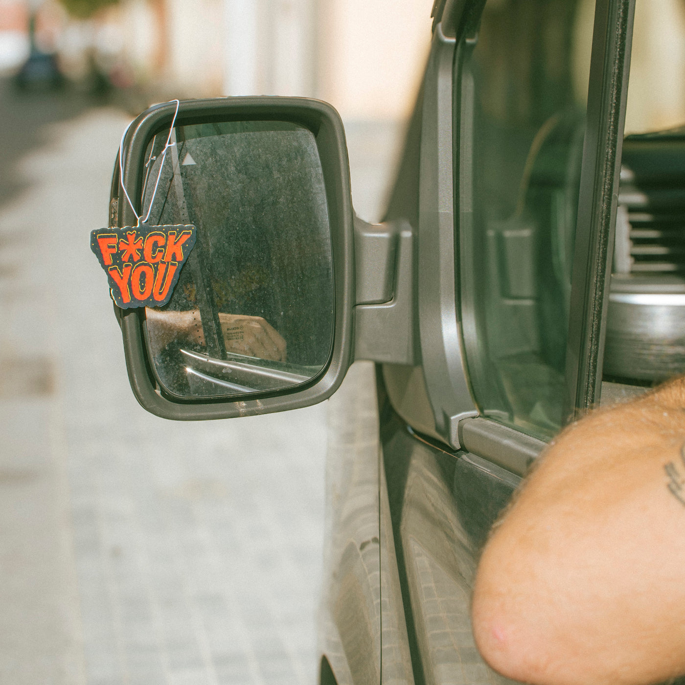Car side mirror with a 'F*ck You' air freshener attached