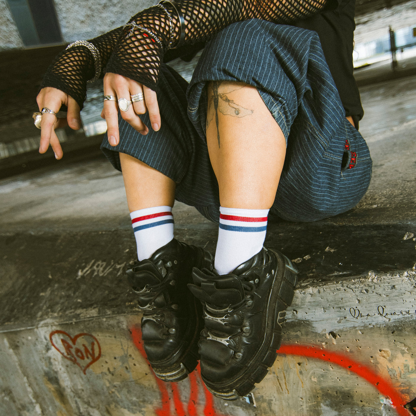 Person sitting while wearing ankle socks with two red and blue stripes by american socks